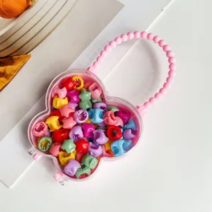 Gros plan de mini pinces à cheveux colorées rangées dans une boîte transparente en forme de fleur.