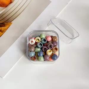 Gros plan de mini pinces à cheveux colorées dans une boîte transparente, accessoire de coiffure.