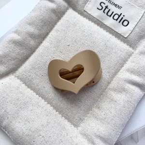 Detail shot of a minimalist matte hollow heart hair claw clip in beige, stylish hair accessory.