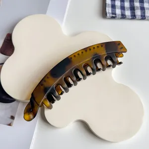Detailed shot of a stylish leopard print banana hair clip resting on a white cloud tray.