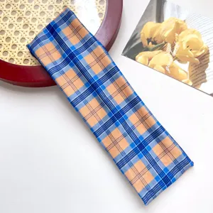 Gedetailleerd uitzicht op de klassieke sporthaarband met ruitjespatroon in blauw en oranje.