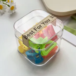 Nahaufnahme einer klaren Plastikbox gefuellt mit bunten Mini Haarklammern zum Frisieren.