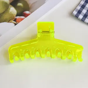 Nahaufnahme Detail der neongelben Jelly Haarklammer mit transparenter Textur und Feder.
