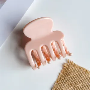 Detail van de roze acryl haarclip in close-up, met een glad oppervlak en een stevige gripstijl.