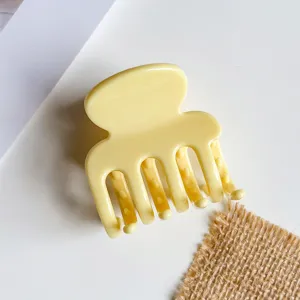 Detail van lichtgeel haarspeldje, kleine kunststof haakklem voor een elegant half opgestoken kapsel.