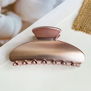 Primo piano dettagliato di un fermaglio per capelli in oro rosa metallico con texture galvanica.