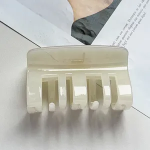 Close-up detail shot of a milky white acrylic hair claw clip, elegant minimalist design.