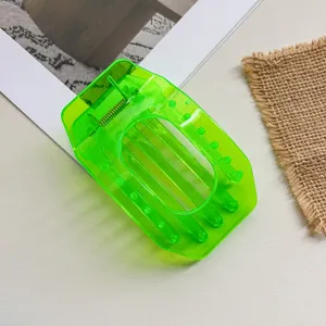 Detail shot of bright green transparent flat hair claw clip, hollow oval design for women.