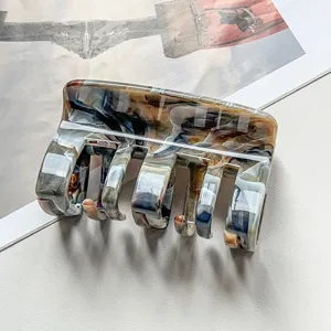 Close-up detail of the stylish marble pattern hair claw clip, showing its unique multi-tooth texture.