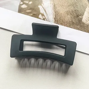 Minimalistische matte schwarze rechteckige ausgehöhlte Haarklammer, Styling-Detail.