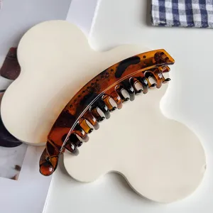 Detail view of a stylish tortoiseshell banana hair clip with a curved tooth design for ponytails.