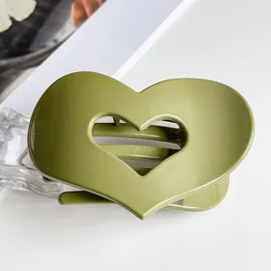 Close-up detail of a stylish green hollow heart hair claw clip, perfect for elegant buns.