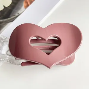 Heart shaped hair claw clip detail shot, elegant mauve pink shark clip for daily hair styling.
