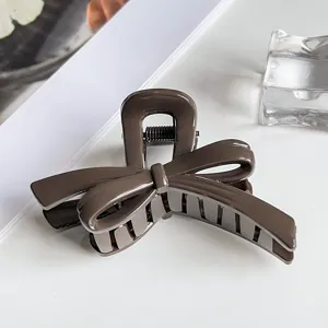Glossy dark brown bow hair claw clip detail, elegant hairpin accessory for styling.