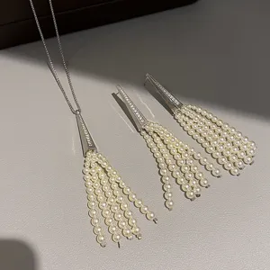 Detailed shot of silver geometric zircon triangle tassel pearl necklace and earrings set.
