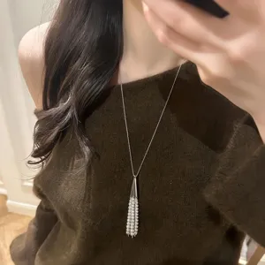 Elegant long silver-tone chain necklace with a chic conical tassel and delicate pearl drops.