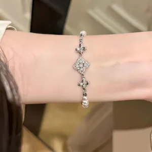 Elegant silver tone clover flower and pearl bracelet, delicate fashion jewelry for women.