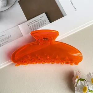 Primo piano del fermacapelli arancione trasparente decorato con fiori e rivista di stile.
