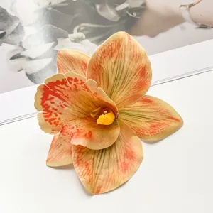 Nahaufnahme einer lebendigen orangen Kunst-Orchideen-Haarspange, Boho-Urlaubsaccessoire.