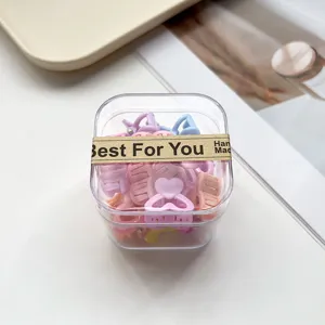 Gros plan de pinces à cheveux cœur colorées dans une boîte transparente, accessoire mignon.