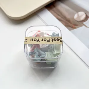 Gros plan de mini pinces à cheveux dans une boîte transparente, jolis clips colorés pour coiffure.