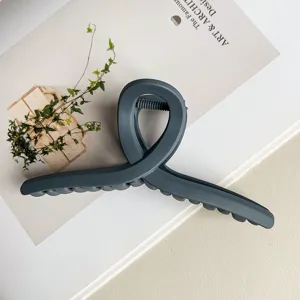 Detailansicht einer matten dunkelgrauen Haarklammer mit Kreuzdesign für Frisuren.