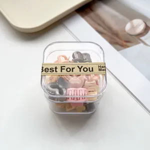 Gros plan de mini pinces à cheveux colorées en boîte transparente avec formes mignonnes pour le coiffage.