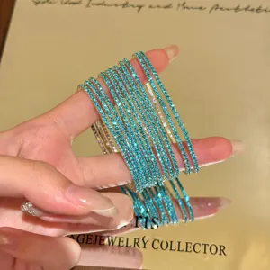Primo piano dettaglio di bracciali elastici impilati in strass blu scintillanti con finitura in cristallo.