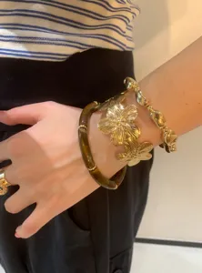 Λεπτομερές κοντινό πλάνο με boho βραχιόλια από χάντρες και χρυσά λουλούδια στον καρπό.