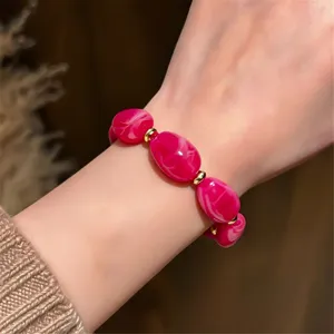 Close-up view of hot pink marbled beaded bracelet with gold spacers worn on wrist elegant detail.
