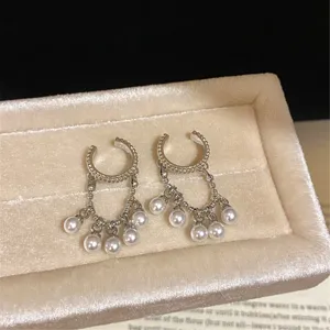 Close-up detail of silver C-shape pearl tassel clip-on earrings, elegant fairy style.