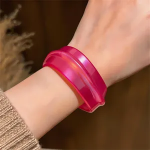Close-up of the bright magenta acrylic cuff bracelet, showing its glossy contoured shape.
