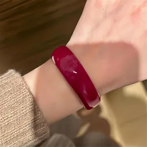 Detailed shot of rose red acrylic round bangle, glossy finish, elegant fashion hand jewelry.