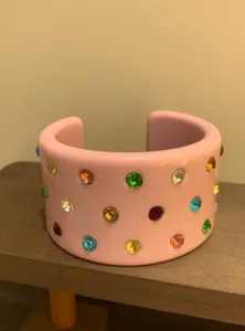 Pink wide cuff bracelet featuring vibrant colorful rhinestone polka dots, minimalist detail.