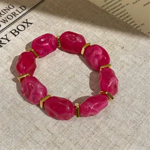 Detail view of a stylish hot pink marbled acrylic bead and gold spacer elastic bracelet.