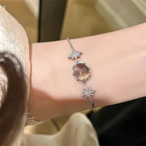 Gros plan détaillé du bracelet en argent avec zircone étoile et pendentif rond au poignet.