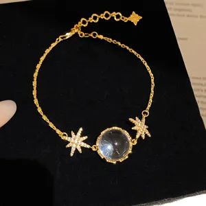 Bracelet tendance avec pendentif boule en verre transparent et zircone etoilee dore