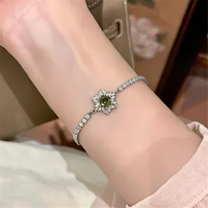Filigranes Silber Zirkonia Armband mit grünem Kristallblumen Mittelstück am Handgelenk.
