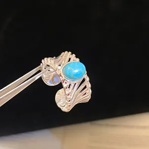 Vue détaillée d'une bague ouverte en argent de style vintage avec une pierre turquoise ovale.