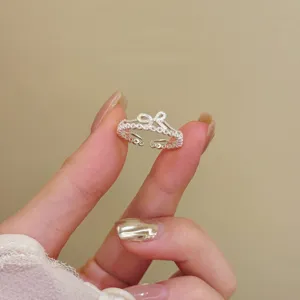 Vue rapprochée et détaillée de la bague ouverte argentée ajourée avec un design de nœud fin.