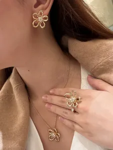 Gold flower jewelry set detail showing hollow floral earrings, necklace and open ring.