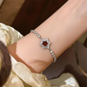Nahaufnahme des glitzernden Zirkonarmbands am Handgelenk mit einem funkelnden roten Stein.