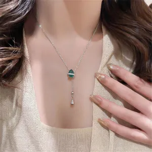 Silver tone necklace featuring a green teardrop zircon stone, crystal ring and tassel drop design.