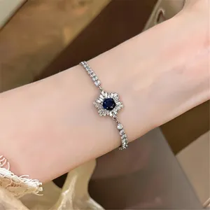 Detailaufnahme eines silberfarbenen Armbands mit dunkelblauer Kristallblume am Handgelenk.