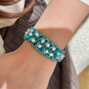 Vista de cerca del detalle de la pulsera de múltiples hilos tejida con cuentas turquesas y perlas.