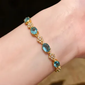 Detailed close-up of an 18k gold plated blue oval stone and floral zircon bracelet wristwear.