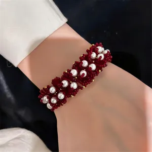 Detalle de primer plano de pulsera tejida a mano de cuentas rojas y perlas, elegante joya.