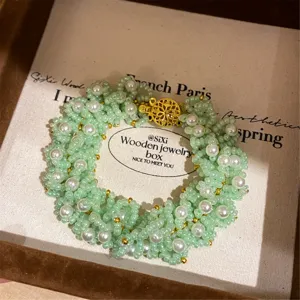 Hermosa pulsera de perlas tejidas verdes con cierre dorado vista detallada en caja elegante
