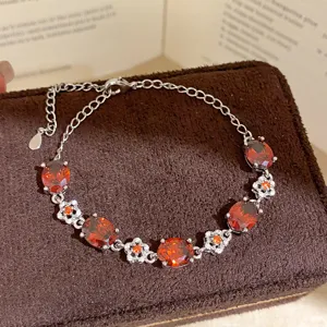 Detailed view of luxury silver bracelet featuring vibrant red oval zircon and crystal flower charms.