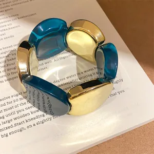 Detailed shot of a chunky resin and metallic gold geometric link bracelet, modern chic style.